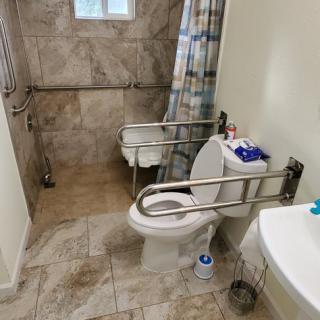 An accessible bathroom with grab bars, a shower area, and a sink.