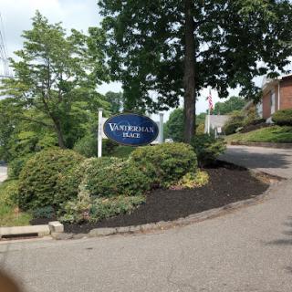 Entrance sign to a property, surrounded by greenery and a winding road.
