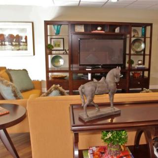 A cozy living room featuring a television, sofa, and decorative horse sculpture.