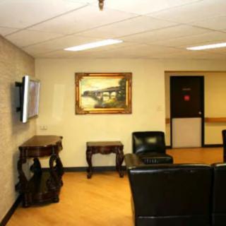 A waiting room with leather chairs, a painting on the wall, and a television.