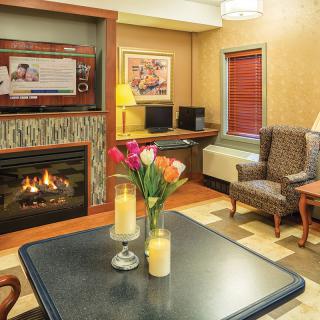 A cozy living room interior featuring a fireplace, table with flowers and candles, and a comfortable seating area.