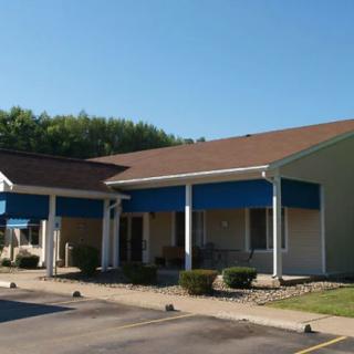 A suburban commercial building with a blue awning and ample parking space.