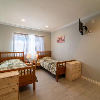 A cozy bedroom featuring twin wooden beds, neutral decor, and a wall-mounted television.