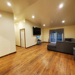 A spacious living room with hardwood flooring, featuring a television and a sofa set near a window.