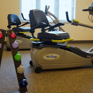A well-equipped fitness area featuring a recumbent bike and weight rack.