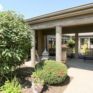 A sunny outdoor patio with lush greenery and decorative columns.