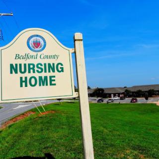 A sign for the Bedford County Nursing Home, surrounded by a grassy area and clear blue skies.