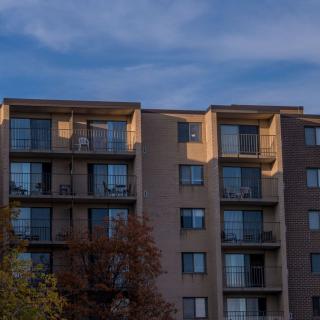An apartment building with balconies under a clear blue sky during sunset.