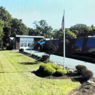 A clear view of a building with a flagpole in front, surrounded by well-maintained lawns and trees.