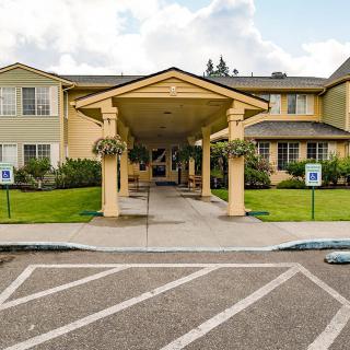 Entrance of a building with covered walkway and landscaped surroundings.