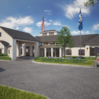 A modern building entrance featuring landscaped grounds and flags.