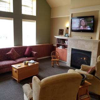 A cozy living room featuring a comfortable sofa, a television mounted on the wall, and a warm fireplace.