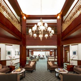 A luxurious lobby featuring elegant wood paneling and a grand chandelier, with comfortable seating areas.