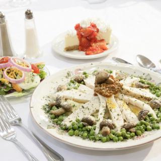 A plated meal featuring chicken with cream sauce and peas, accompanied by a side salad.