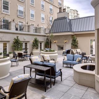 A stylish outdoor patio with comfortable seating and greenery in an urban setting.
