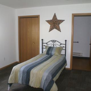 A simple bedroom featuring a single bed with striped bedding and a large star decoration on the wall.