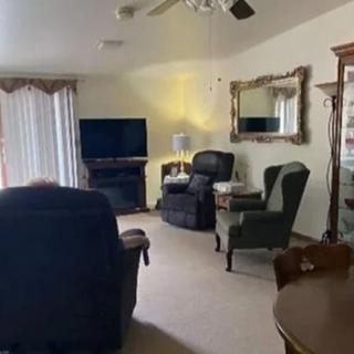 A cozy living room with armchairs, a television, and a decorative mirror.