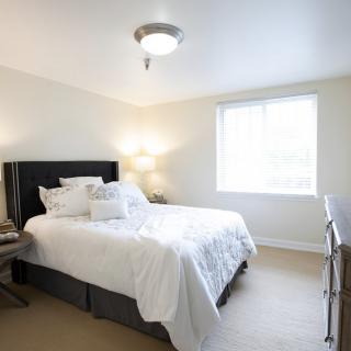 A bright and minimalist bedroom with a neatly made bed and ample natural light.