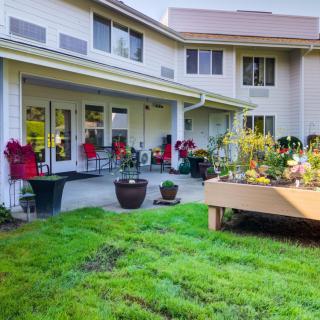 A well-maintained garden area with lush grass and potted plants outside a residential building.