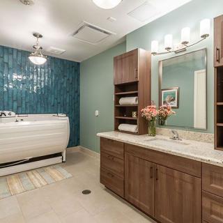 A modern bathroom with a sleek bathtub and wooden vanity, featuring a large mirror and decorative elements.