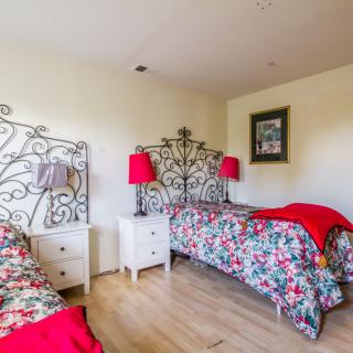 A cozy bedroom with twin beds featuring floral bedding and decorative red accents.