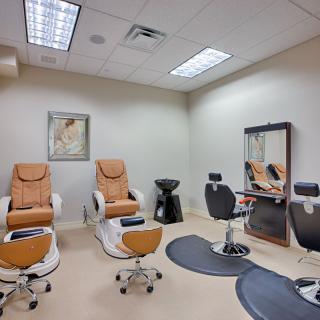 A well-equipped salon room featuring pedicure chairs, styling chairs, and a mirror.