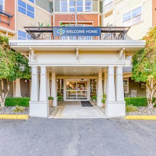 Front entrance of a residential building with a welcome sign and surrounding greenery.