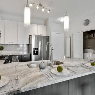 A modern kitchen with stainless steel appliances and a marble countertop.