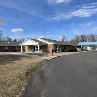 A brick building with a flagpole and an extended driveway under a partly cloudy sky.