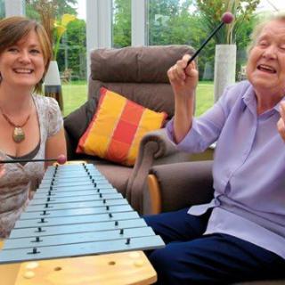 Two people enjoying playing music together on a xylophone.
