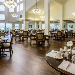 A spacious dining room with elegantly set tables and chandeliers.