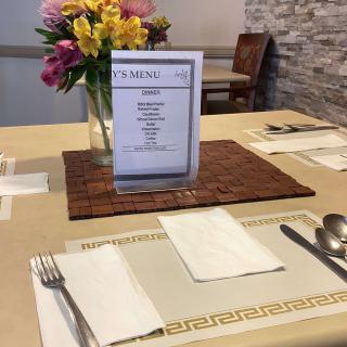 A restaurant table set with a menu and a vase of flowers.