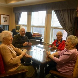A group of seniors enjoying a conversation around a table indoors.
