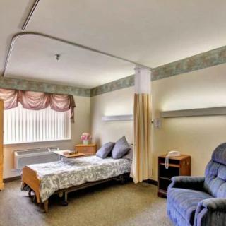 A tidy hospital room with a bed and chair, featuring a window and curtain.