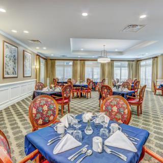 An elegantly set dining room with formal table settings and ornate chairs.