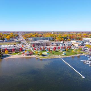 Aerial view of a lakeside town with colorful buildings and a marina during autumn.