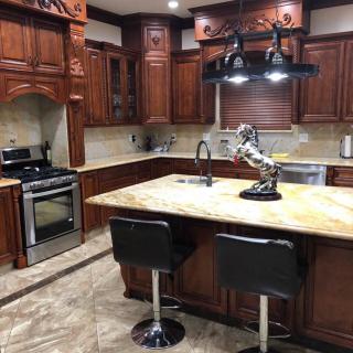 A modern kitchen featuring wooden cabinets, a central island with stools, and sleek lighting.