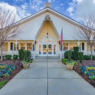 A picturesque church with a manicured garden and pathway under a blue sky.