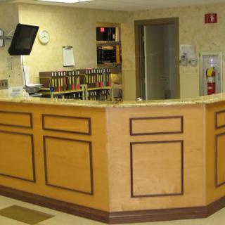 A reception desk in an office setting, featuring a wooden counter and a computer monitor.