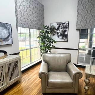 A modern living room with a cozy armchair, large windows, and stylish decor.