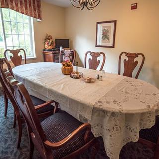 A cozy dining room with a lace-covered table and elegant wooden chairs.
