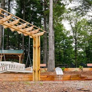 A peaceful outdoor setting featuring a wooden pergola swing among tall trees.