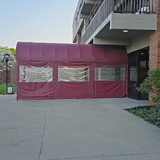 A maroon tent set up at the entrance of a building, providing shelter.