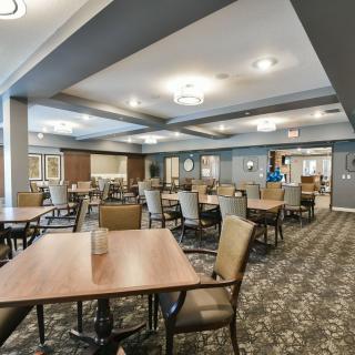 A spacious dining room with neatly arranged tables and chairs, featuring modern interior design and ceiling lighting.