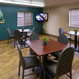 A small dining room with several tables and chairs, a television on the wall, and decorative elements.