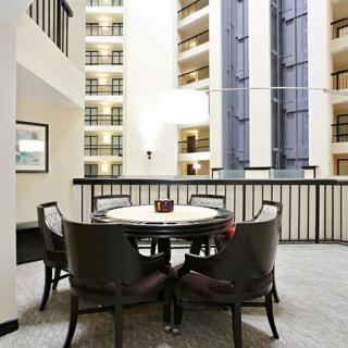 A spacious hotel atrium with a round table and chairs, surrounded by multi-level balconies.