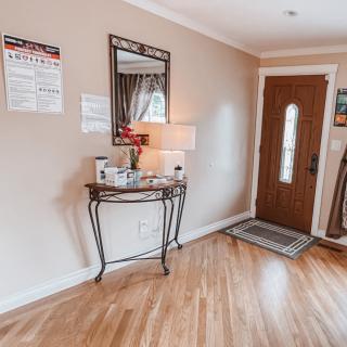 A cozy entryway featuring a console table with a lamp and decor under a wall-mounted mirror.