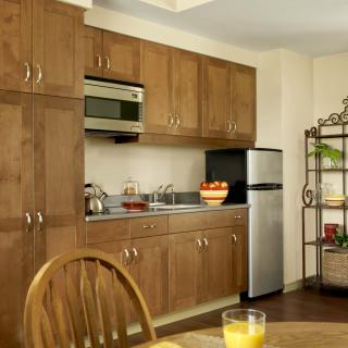 A cozy kitchen with wooden cabinets, a microwave, and a small refrigerator.