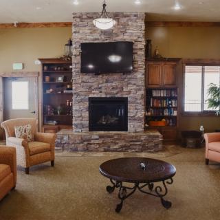 A cozy living room with a stone fireplace, flanked by bookshelves and centered around a round coffee table with comfortable seating.