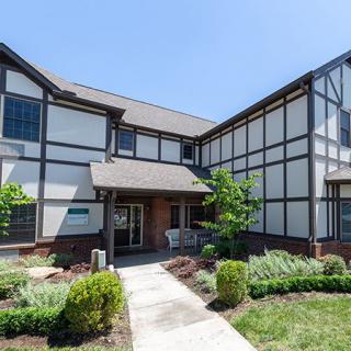 A Tudor-style residential building with manicured landscaping on a sunny day.